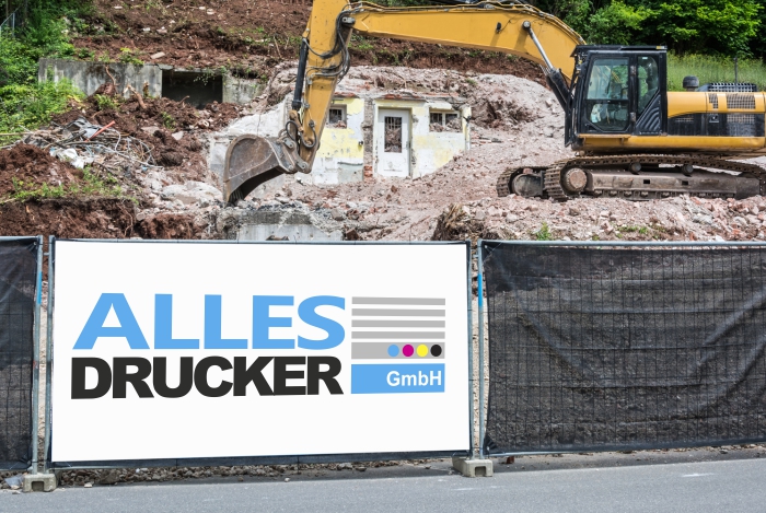 Bauzaunplane mit dem Allesdrucker Logo vor einem Bagger